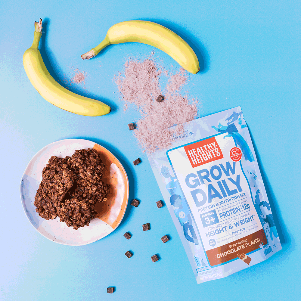 Healthy Heights Grow Daily 3+ Chocolate protein mix bag, bananas, and freshly baked chocolate cookies, showcasing a fun protein powder baking recipe idea - Healthy Heights