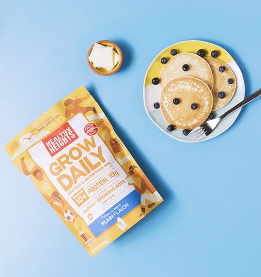 Healthy Heights Grow Daily Protein Shake for Boys – Ages 10+ - Pediatrician-developed Healthy Heights Grow Daily protein shake pack beside a plate with three pancake-style growth shakes. - Healthy Heights